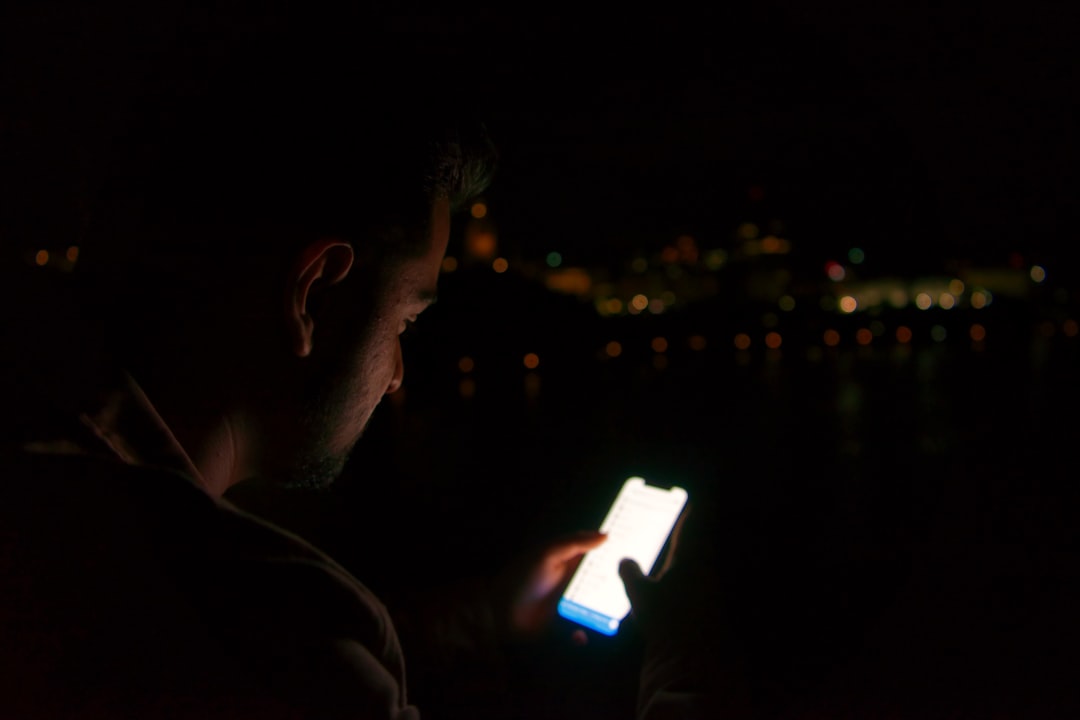 Person chatting with an AI companion on a smartphone in a dimly lit room