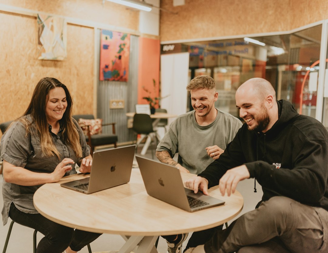 Colleagues collaborating in a hybrid office using AI tools on laptops