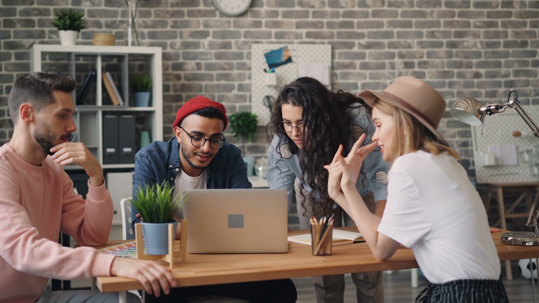 Small business team planning an online marketing strategy around a laptop