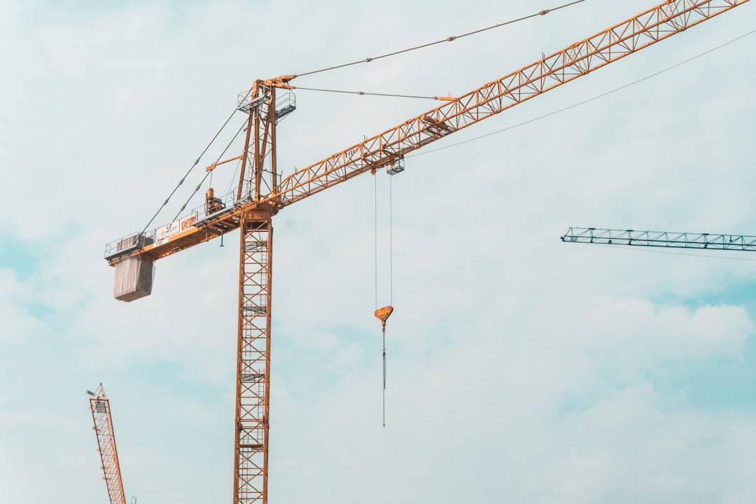Busy construction site with excavators and cranes under a cloudy sky